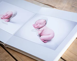 An open newborn album showing a photo of a sleeping baby