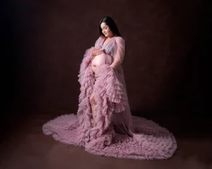 A pregnant woman in a pink gown posing for a photo.