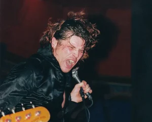 A man singing into a microphone while holding a guitar.