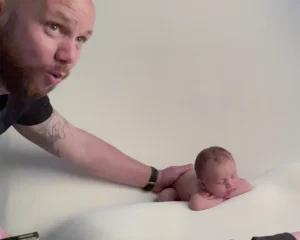 A man is holding a baby in front of a camera.