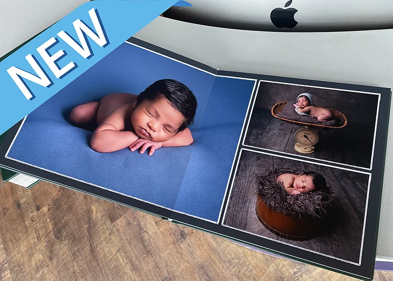 Professional newborn photography prints displayed on a desk with a 'new' placard placed on the upper left corner.